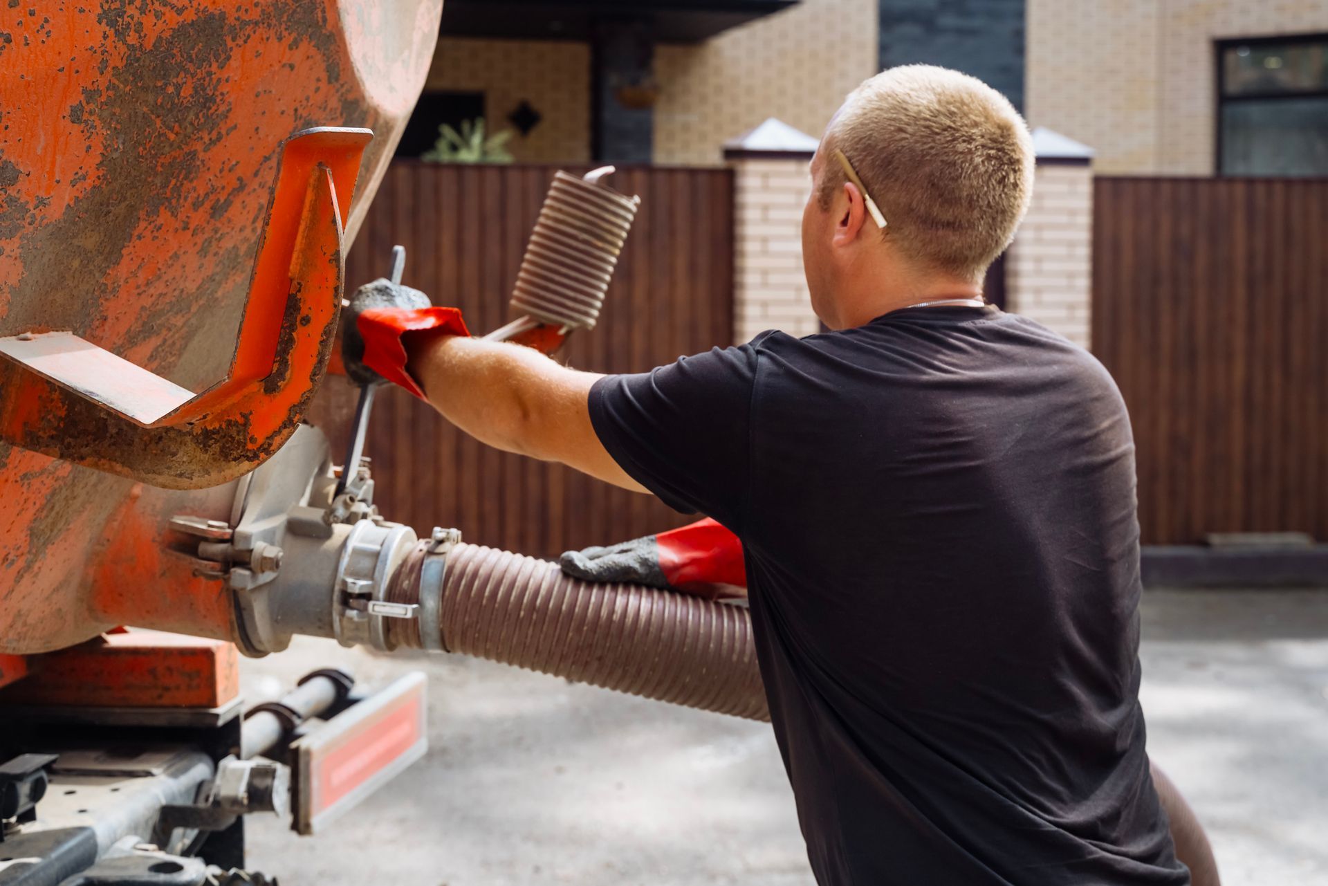 Worker uses a large hose to pump septic waste.