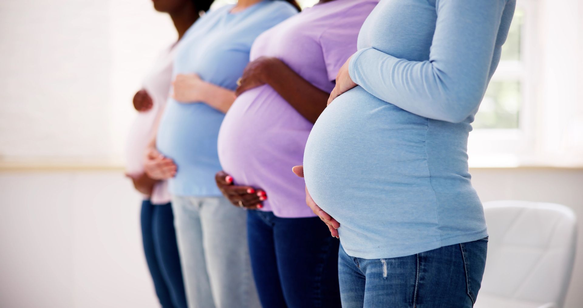 Group of pregnant women cradling their baby bumps