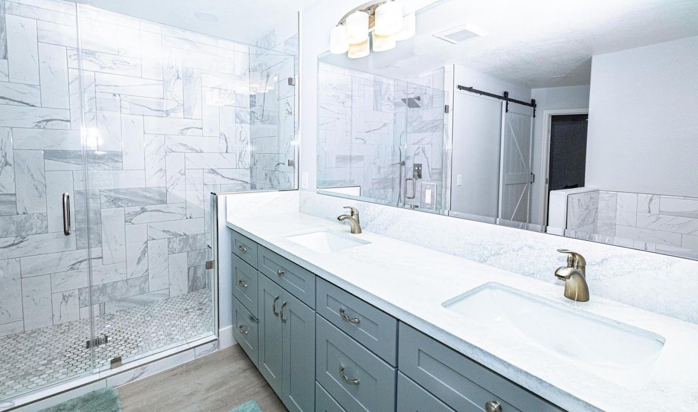 A bathroom with two sinks and a walk in shower.