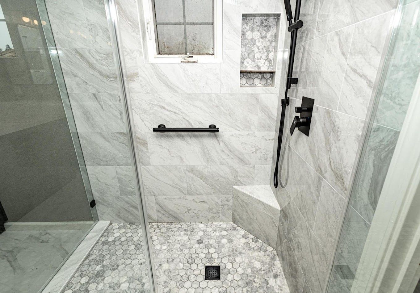 A bathroom with a walk in shower and a window.