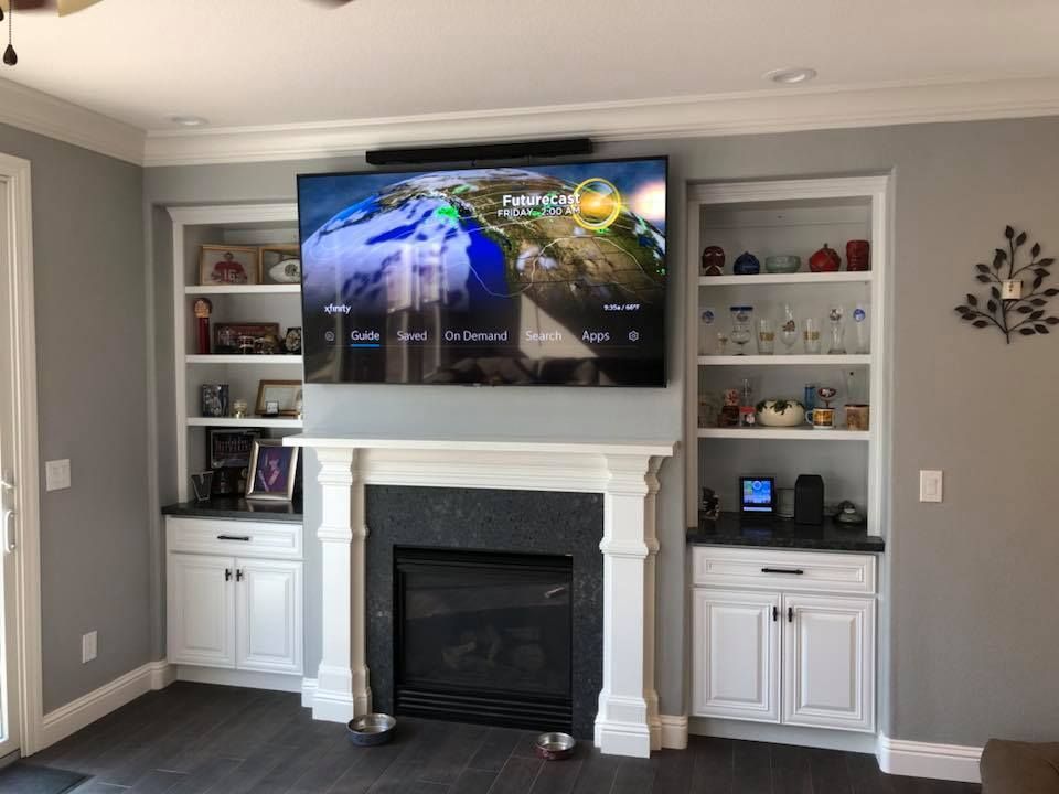 A living room with a couch , chair , television and fireplace.