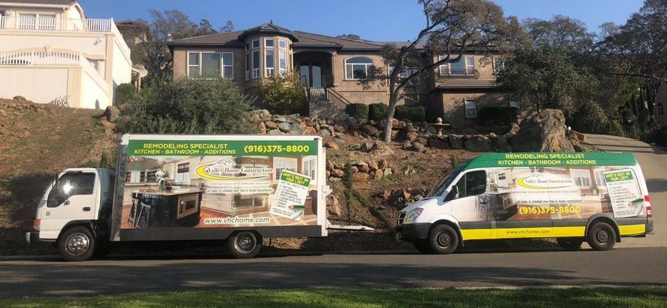 Two moving trucks are parked in front of a house.