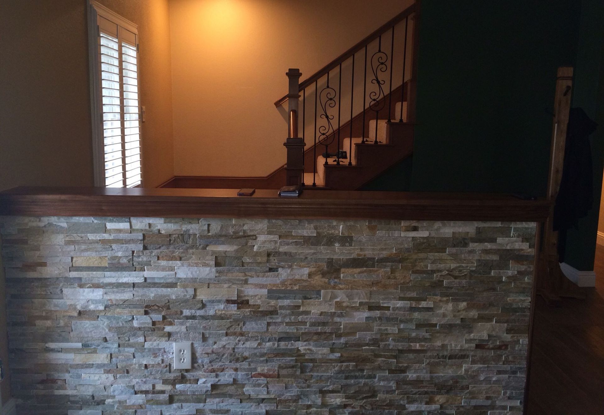 A stone wall in a room with stairs in the background