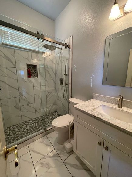 A bathroom with a toilet , sink , shower and mirror.