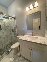 A bathroom with a sink , toilet , shower and mirror.