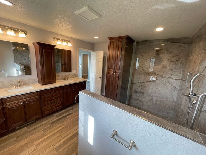 A bathroom with two sinks and a walk in shower.