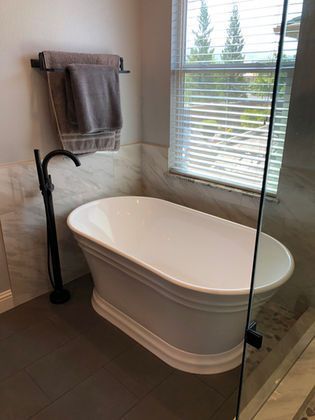 There is a bathtub in the bathroom next to a window.