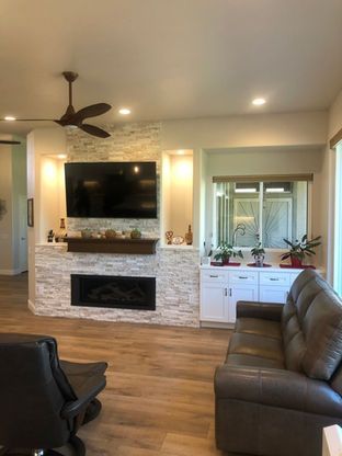 A living room with a couch , chair , television and fireplace.