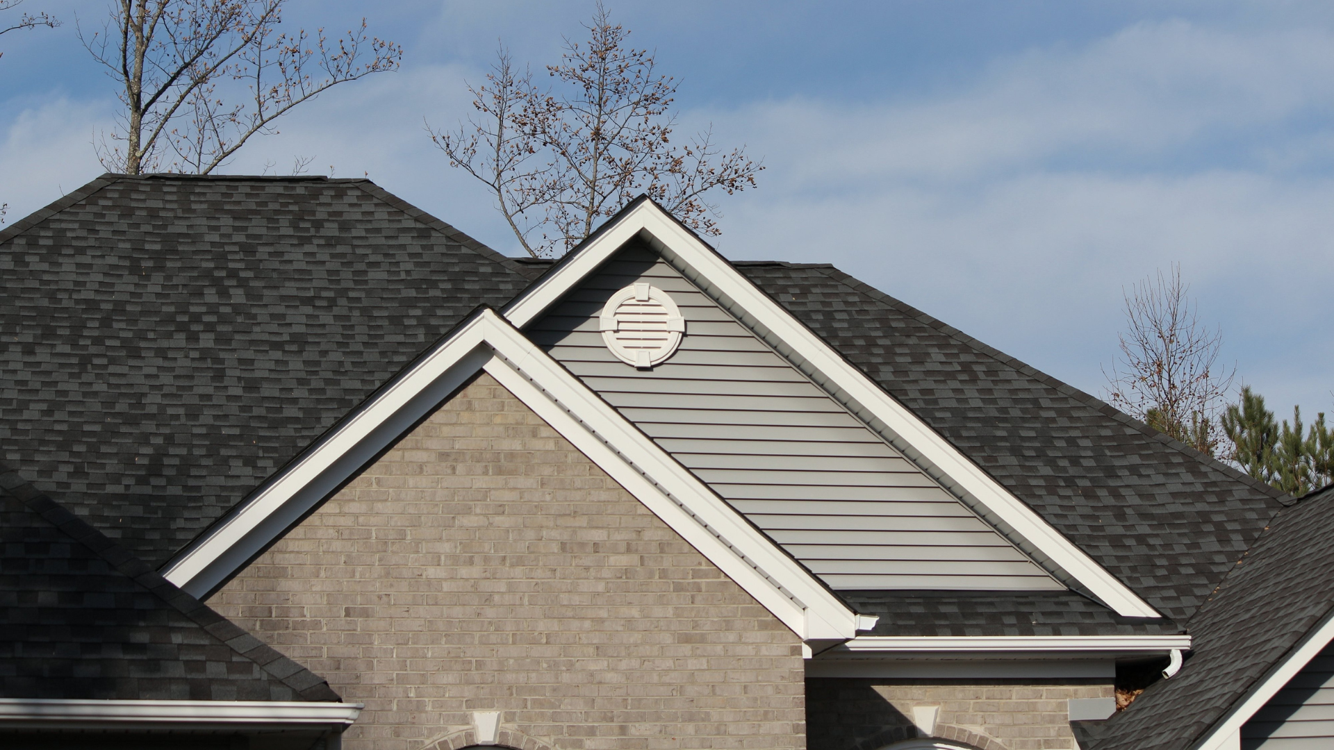 A brick house with a black roof and white trim.