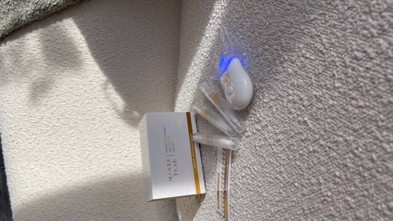 Teeth whitening kit on a white towel: light, gel syringes, and a box.