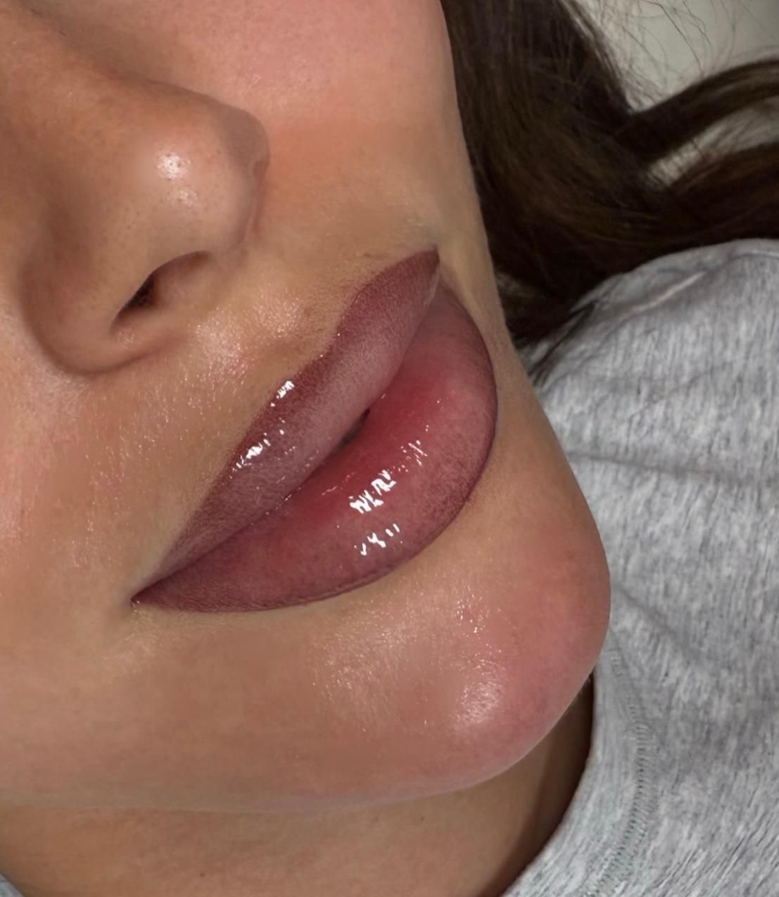Close-up of a person's lips. The lips are enhanced with a reddish pigment and a glossy finish.