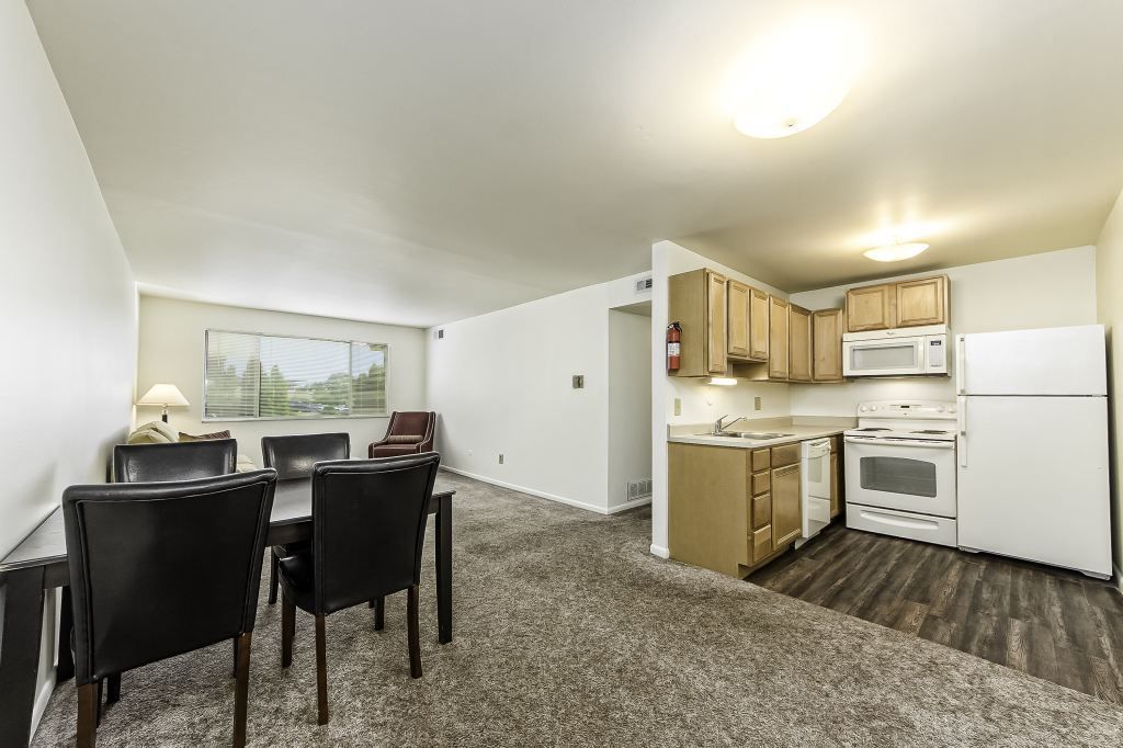 A living room with a dining table and chairs and a kitchen.