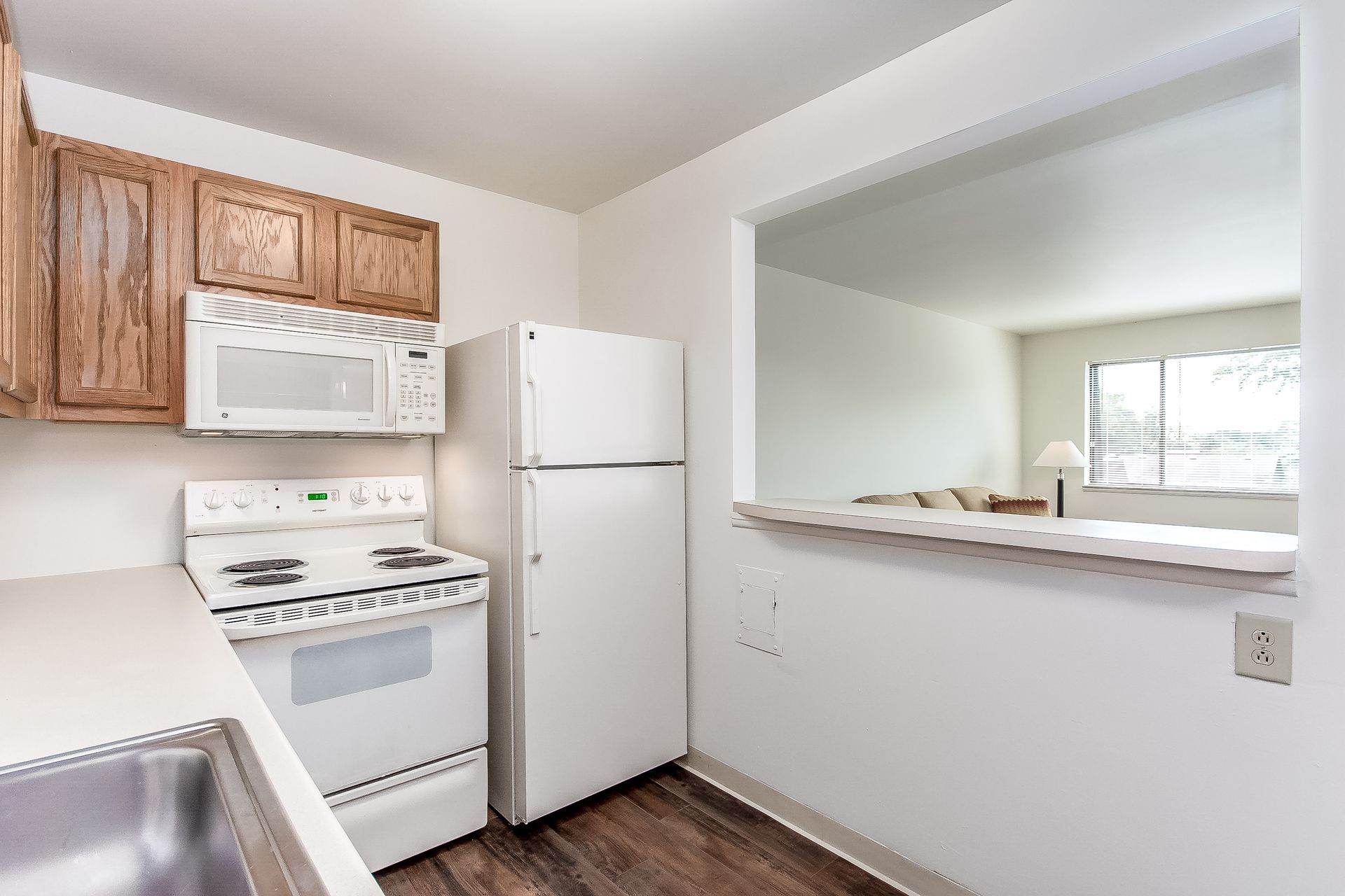 A kitchen with a stove , refrigerator , microwave and sink.