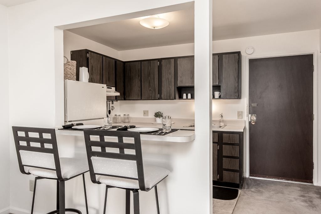 A kitchen with two bar stools and a refrigerator