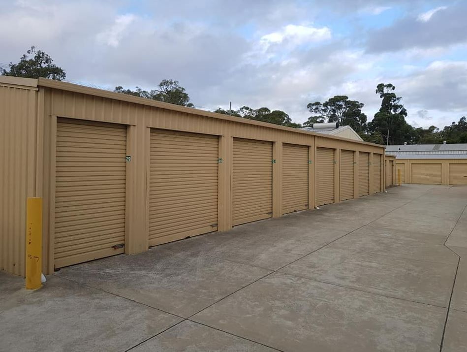 A Row of Beige Storage Units With Roll-up Doors Under a Cloudy Sky — Storage Aus In Rockingham, WA