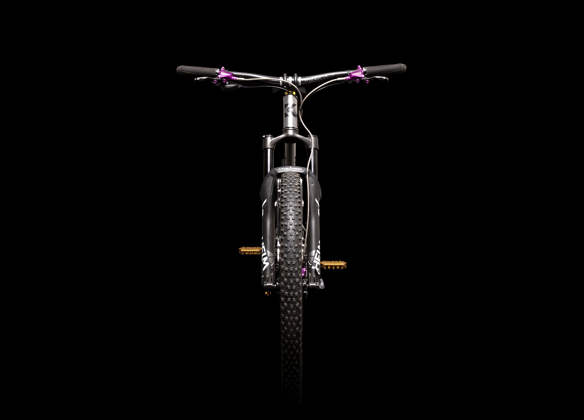 Black mountain bike with purple accents against a black background.