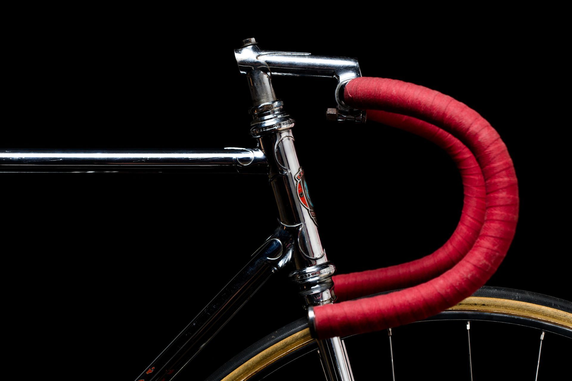 Red and silver vintage road bicycle with white seat and handlebars, black tires.