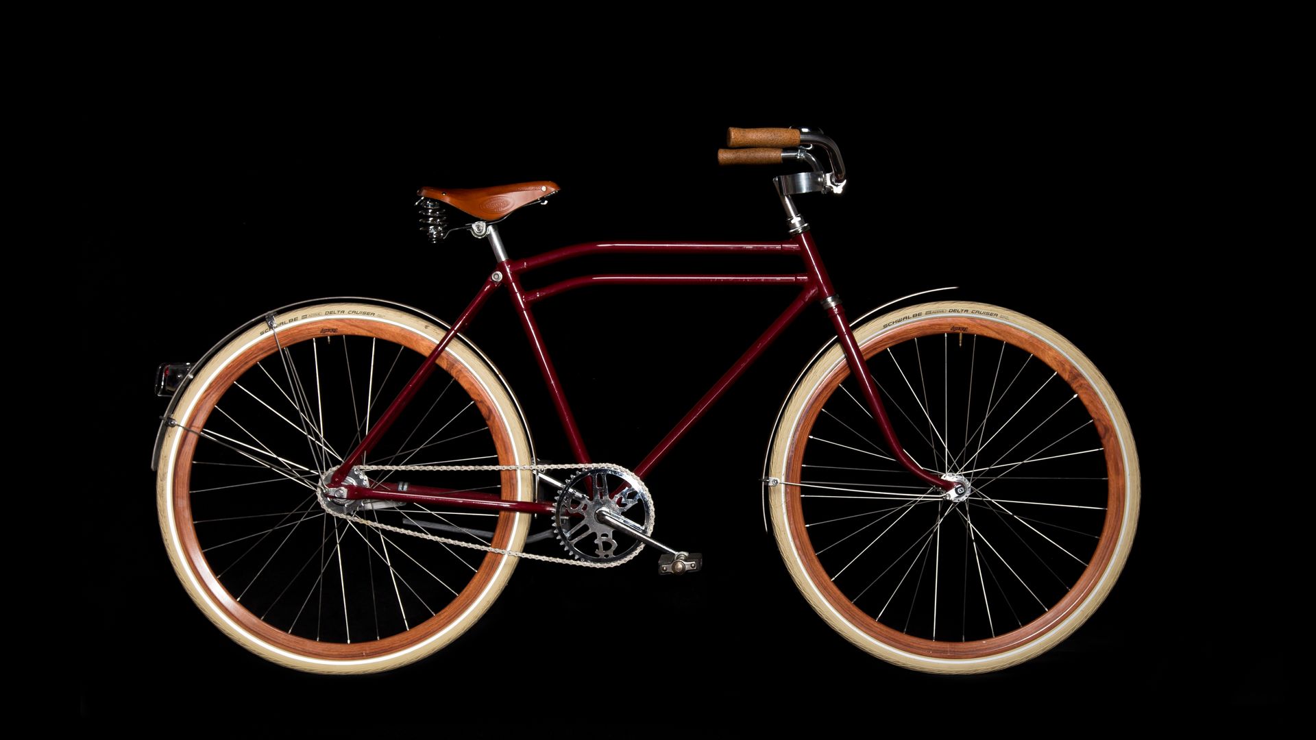 Red vintage bicycle with brown tires and leather seat.
