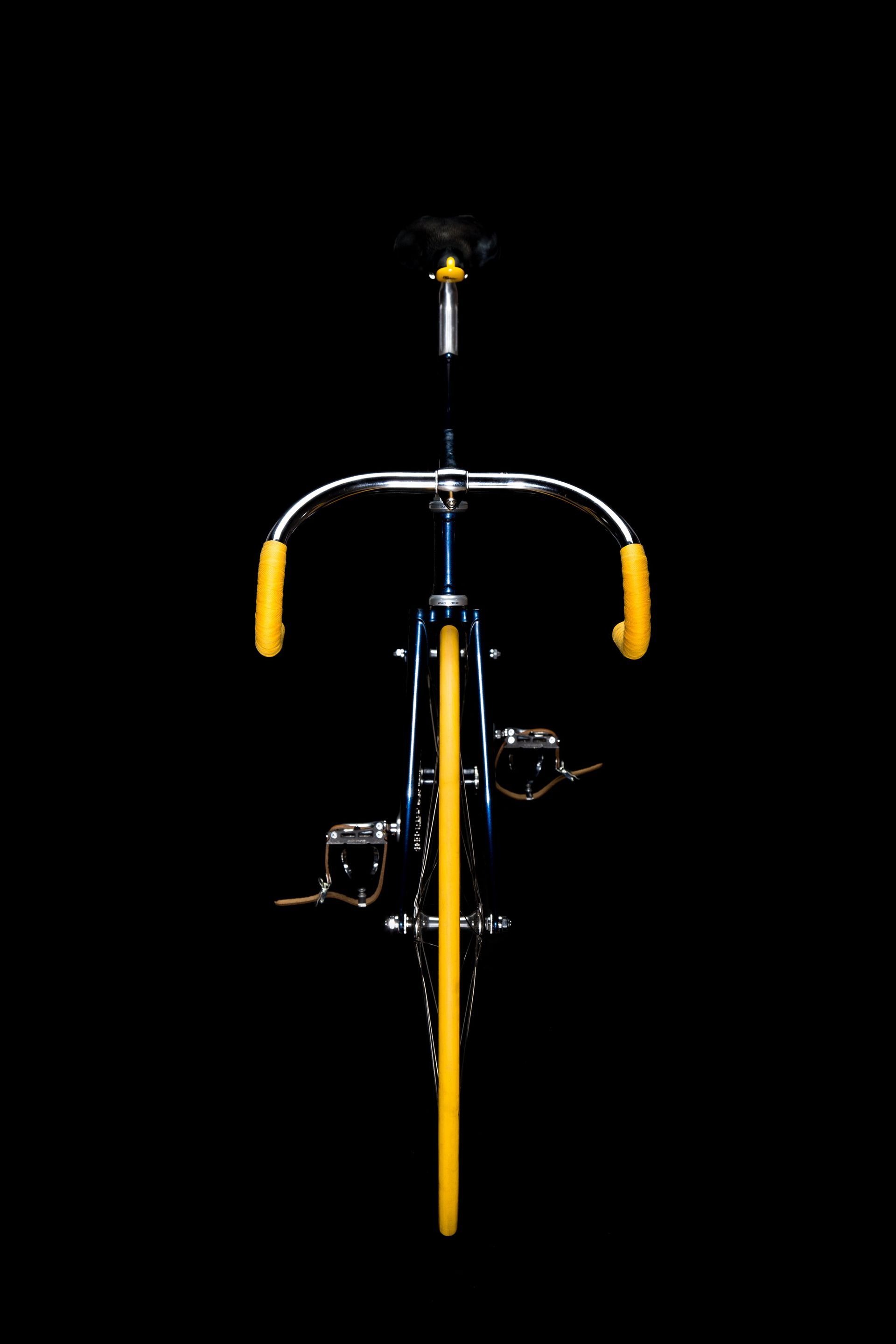 Blue bicycle with yellow accents against a black background.