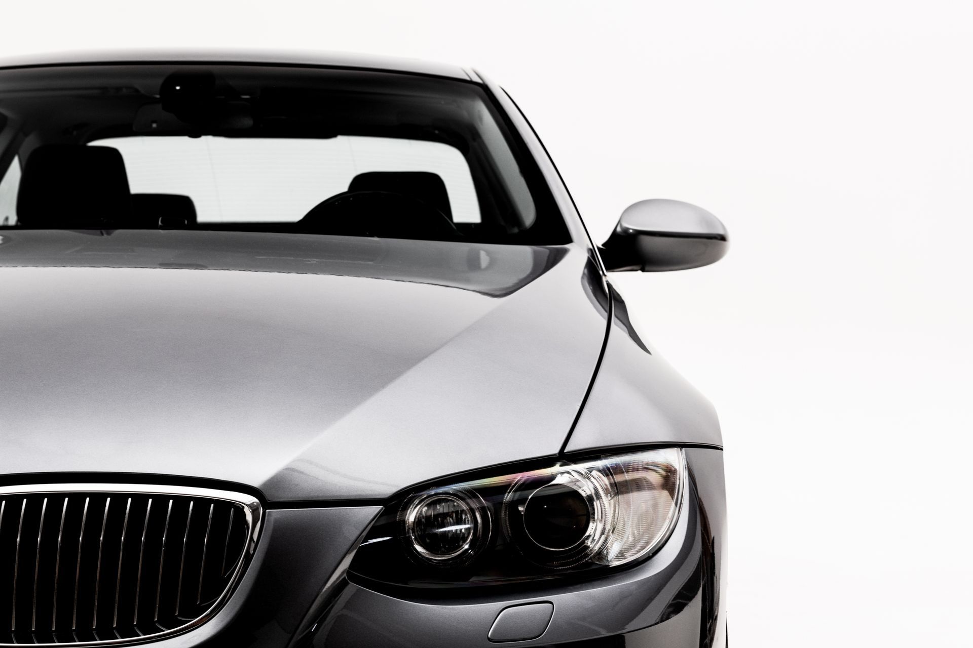 Silver car, front view, headlights illuminated, against a white background.