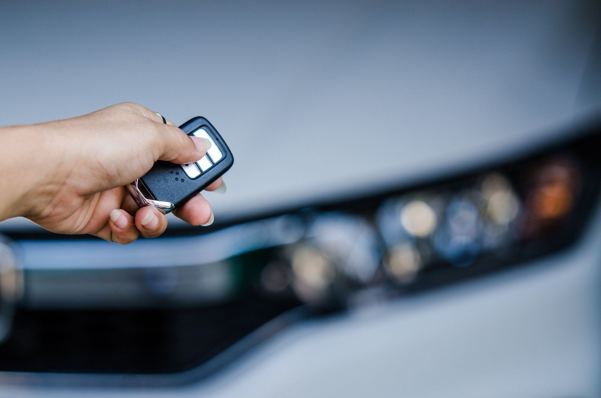a person is holding a remote control in front of a car .