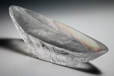 Clear glass sculpture with etched swirling patterns.