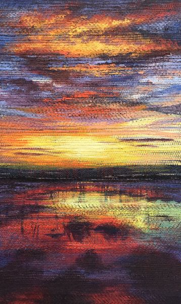 Vibrant sunset over water reflecting colorful sky, orange, yellow, red, purple, and blue hues.