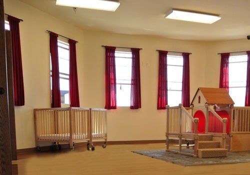 A room with three cribs and a playhouse in it