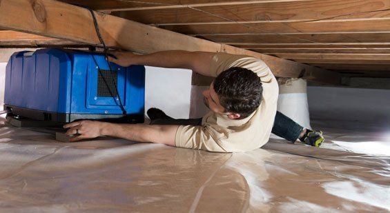A man is crawling under a ceiling in a basement.