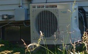 A large air conditioner is sitting outside of a house.