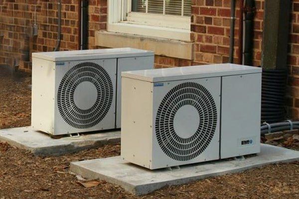 Two air conditioners are sitting outside of a brick building