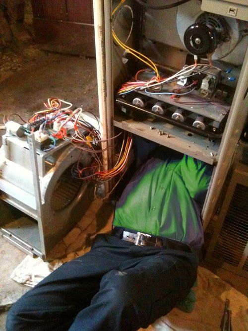 A man is laying on the floor under a heater.