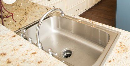 A stainless steel kitchen sink is sitting on top of a granite counter.