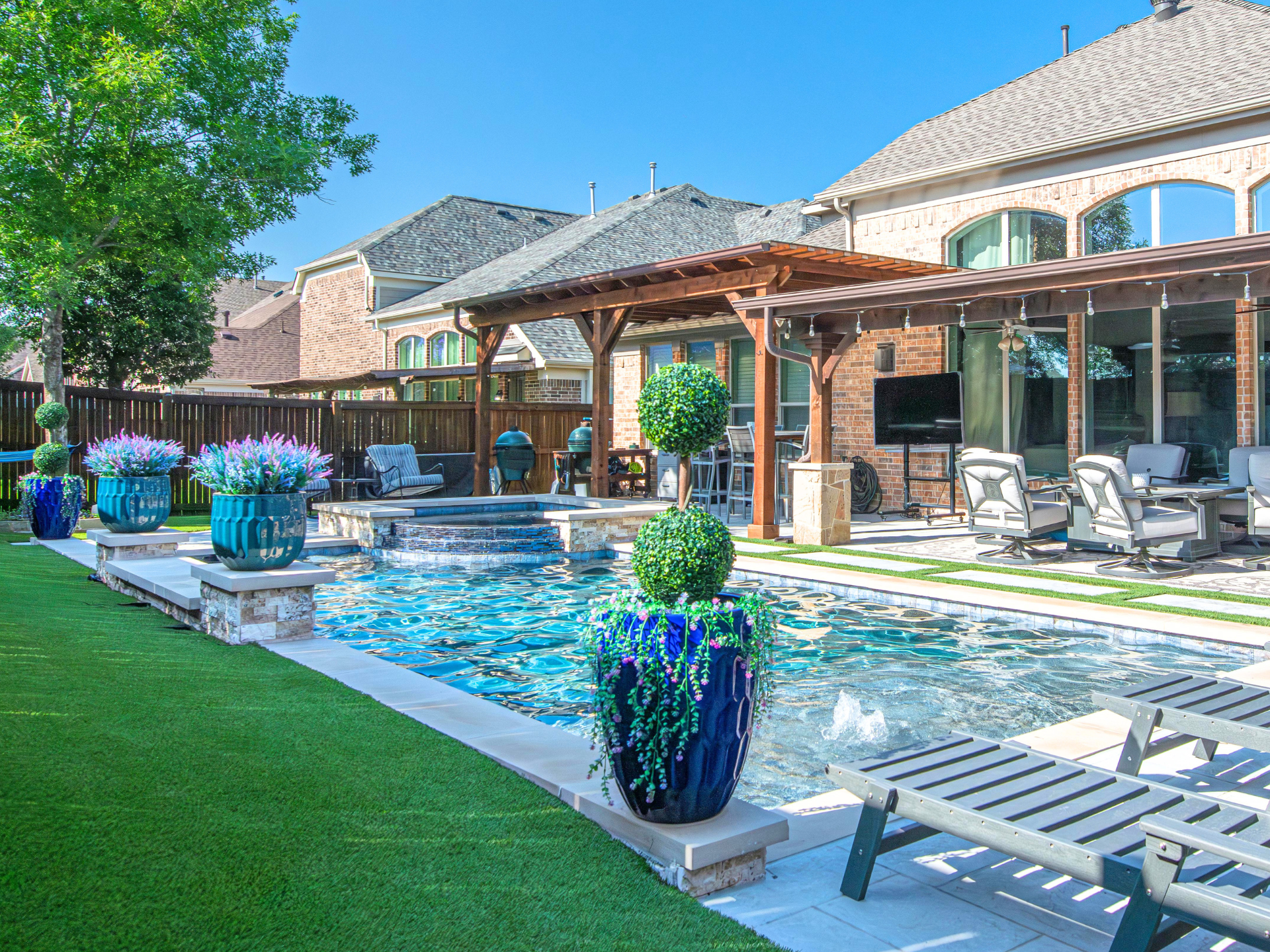 Two professionals in work clothes shake hands over a table with a white hard hat, laptop, and blueprints.