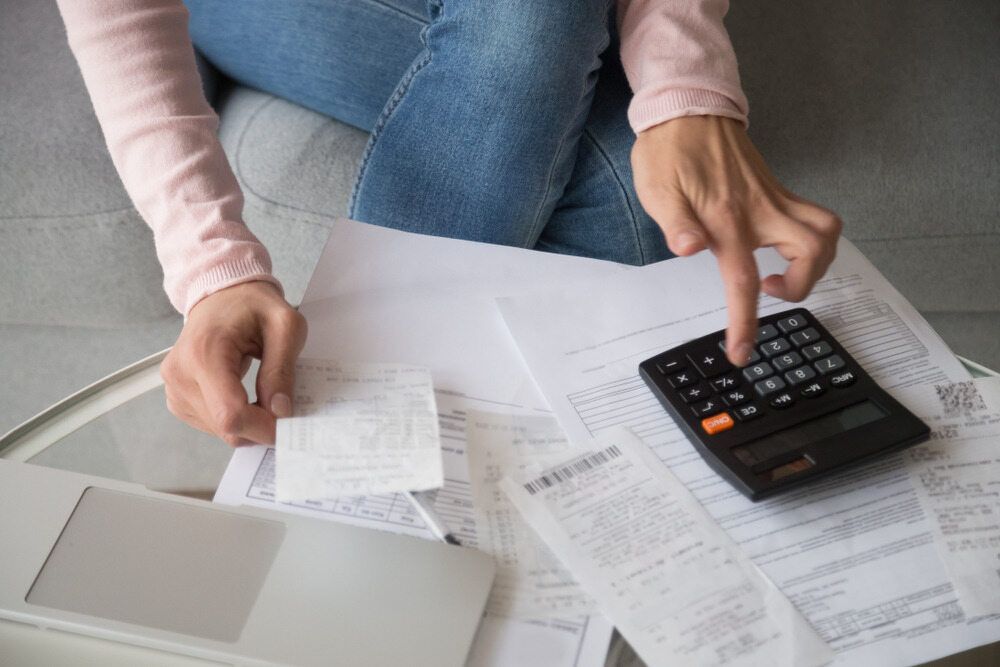 Person Calculating Expenses, Using a Calculator and Receipts Scattered on A Table — SDM Accounting & Taxation Services In Cooroy, QLD