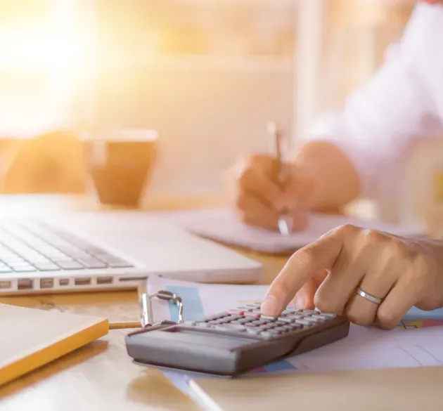An Accountant with a Calculator and Laptop — SDM Accounting & Taxation Services In Cooroy, QLD
