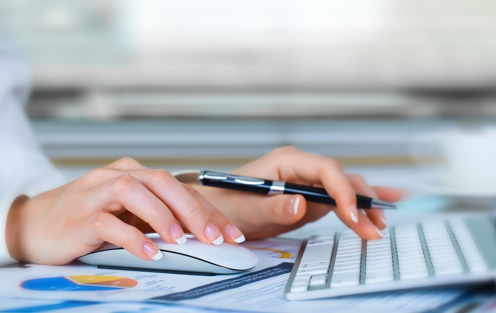 Hands Typing on A Keyboard, Holding a Pen, and Using a Mouse on A Desk with Documents — SDM Accounting & Taxation Services In Cooroy, QLD