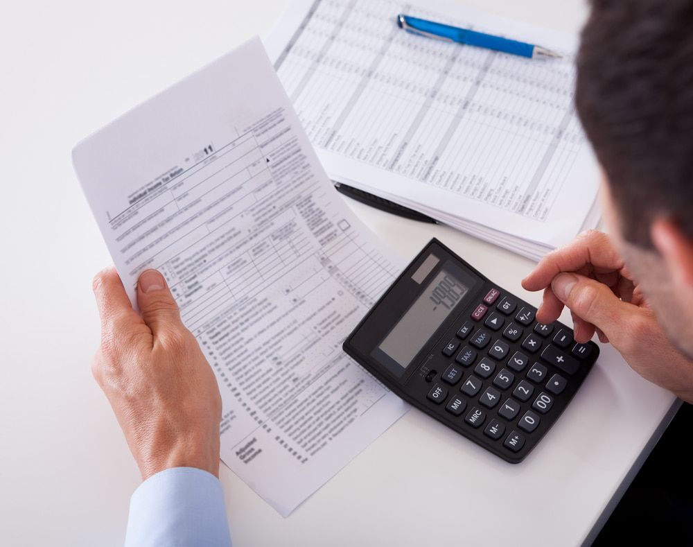 Person Calculating Taxes With A Calculator — SDM Accounting & Taxation Services In Cooroy, QLD