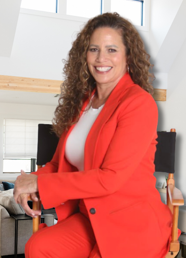 Tina Alzaga in a black jacket stands in a living room with her arms crossed.