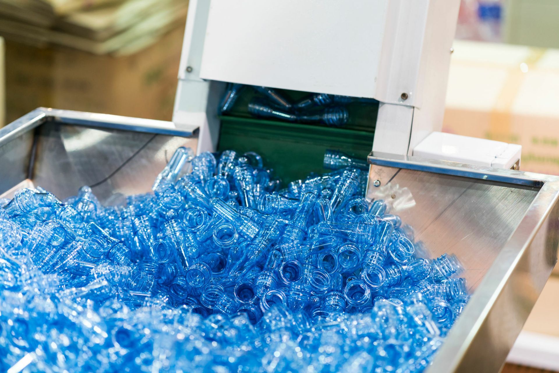 Blue plastic bottles on a conveyor belt being sorted by a machine.