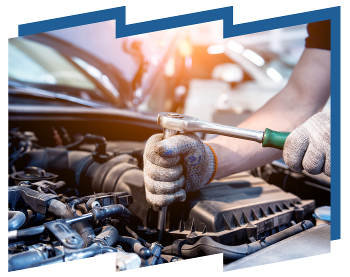 A man is working on the engine of a car with a wrench.
