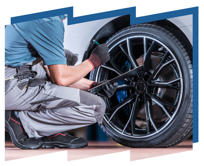 A man is changing a tire on a car in a garage.