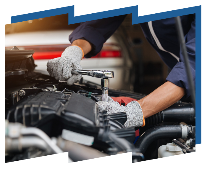 A mechanic is working on a car engine with a wrench.