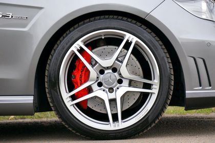A close up of a car wheel with a red brake caliper.