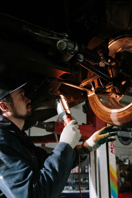 A man is working on the underside of a car in a garage.