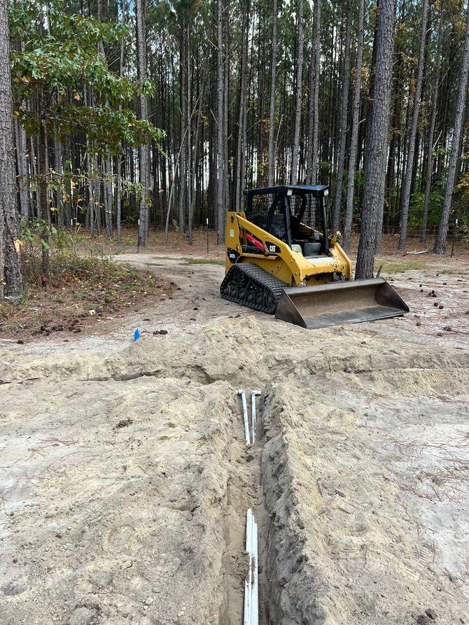 a bulldozer is digging a trench in the middle of a forest .