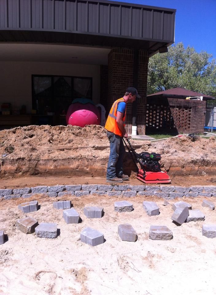 a man is using a machine to level bricks in a yard