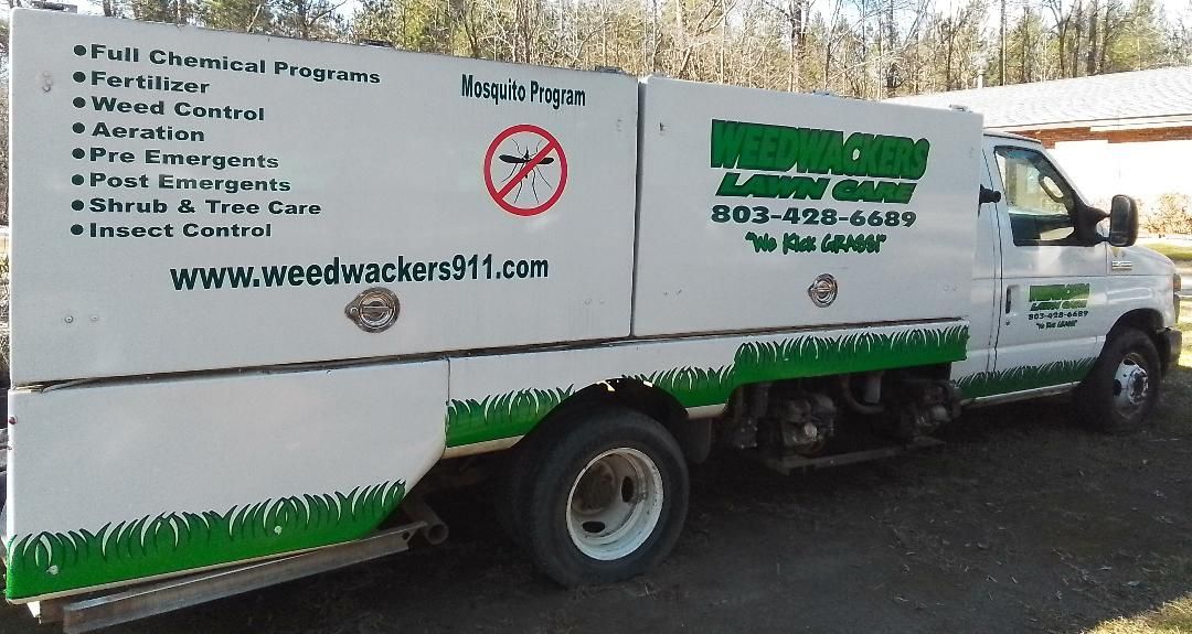 a white and green lawn care truck is parked on the side of the road