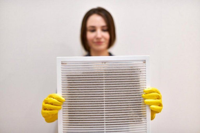 a woman holding a dirty air vent cover