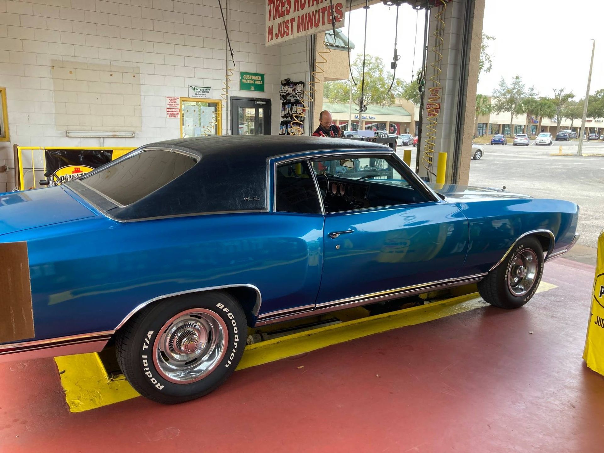 A blue car with a black top is parked in a garage